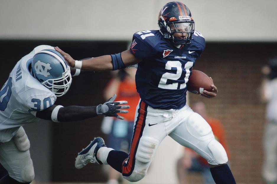 Pearman pushing a defender away as he runs with the ball down the football field