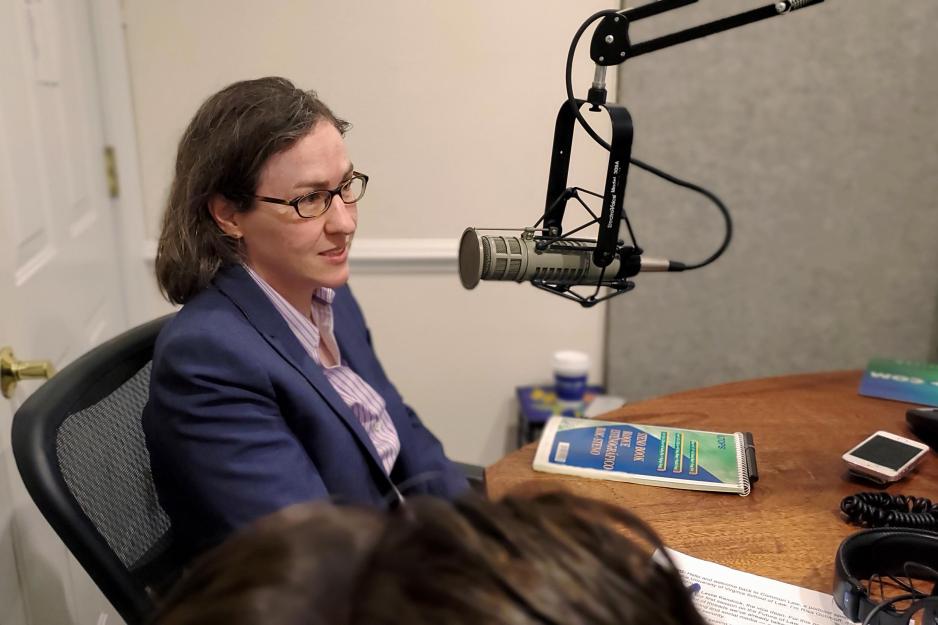 Ashley Deeks talks into a microphone on a podcast