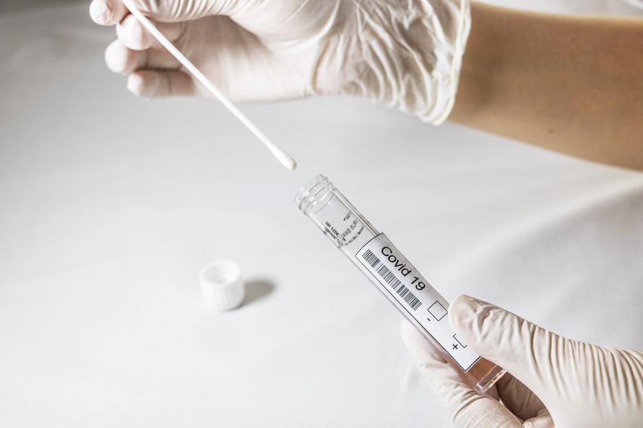 Healthcare working placing a covid-19 swab into a covid-19 test tube