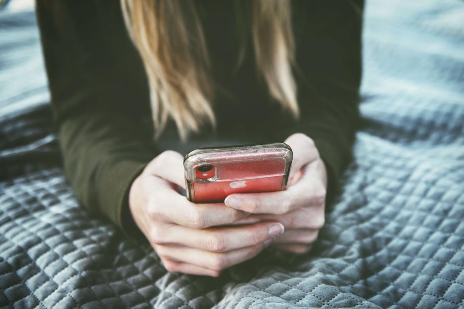 person holding their phone while laying on a bed