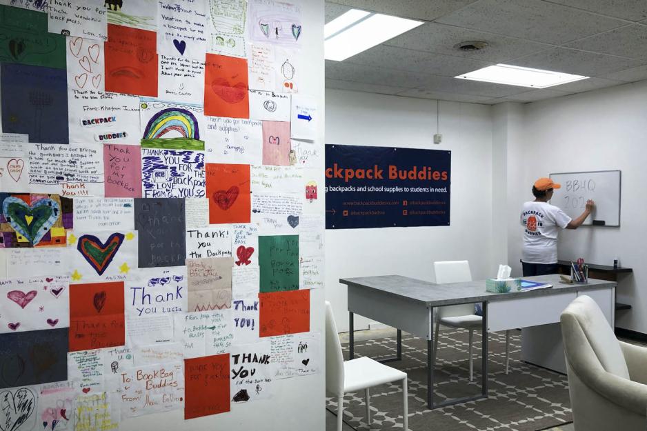 room with notes from children on the left wall and a person writing on a white board, left