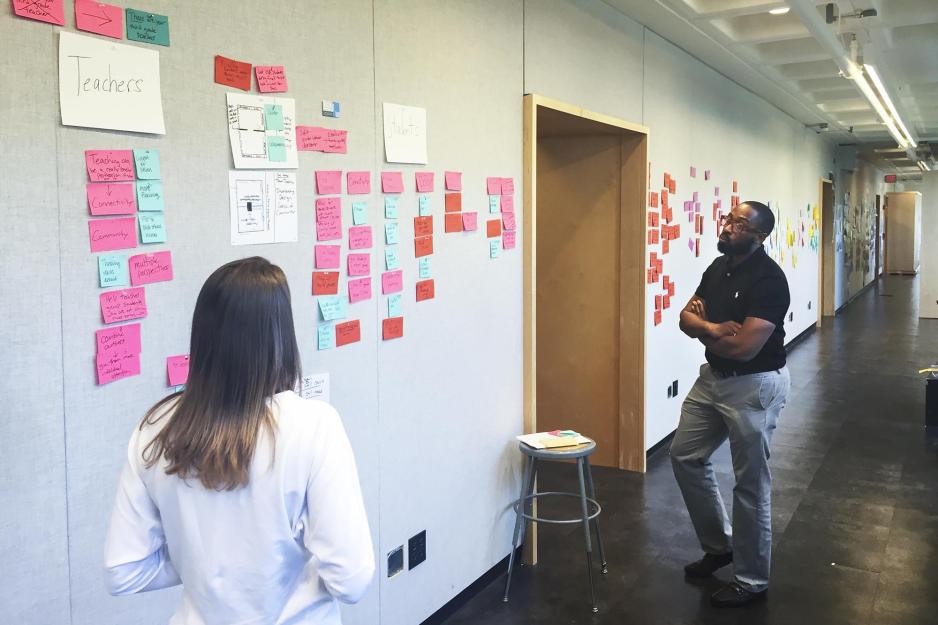 Two people looking at a wall full of sticky notes
