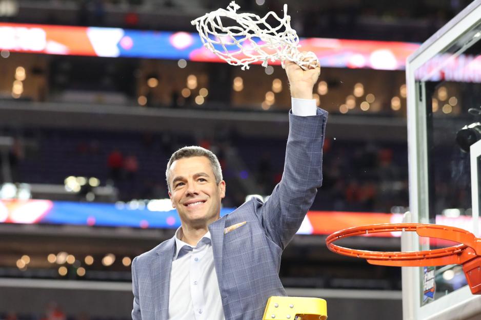 Tony Bennett standing on a ladder raising the cut basketball net high in the air
