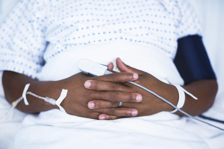 patient sitting in hospital bed with iv in arm, pulse ox on finger, and  blood pressure cuff on arm