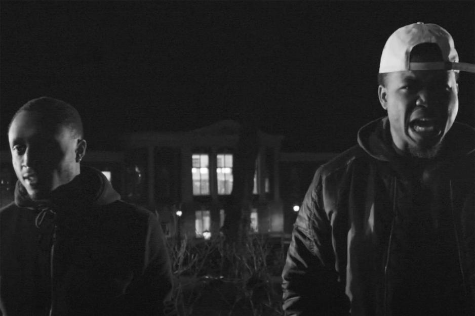Two African American's standing in front of a building at night.  The man on the right is speaking
