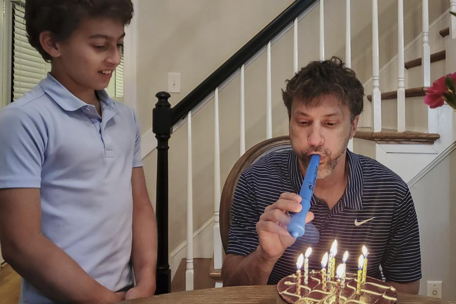 Jake Apelt (left), watches as his dad, Mark (right), uses a Blowzee to blow out candles