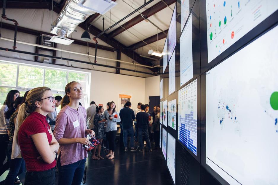 Students looking at screens on a wall that is displaying various data