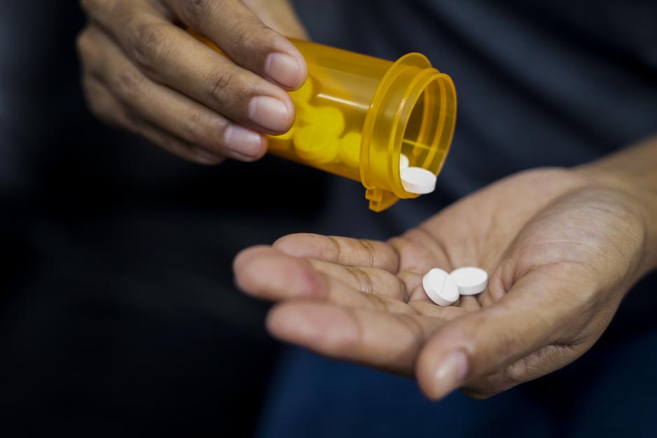 Person pouring pills from a bottle into their hand