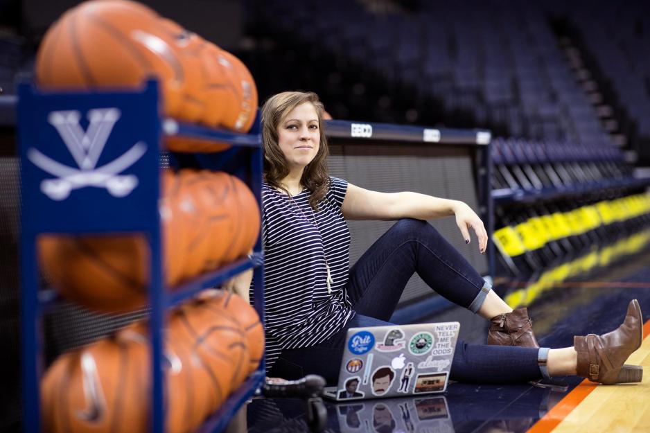 Caroline Darney sits next a rack of basketballs on the basketball court