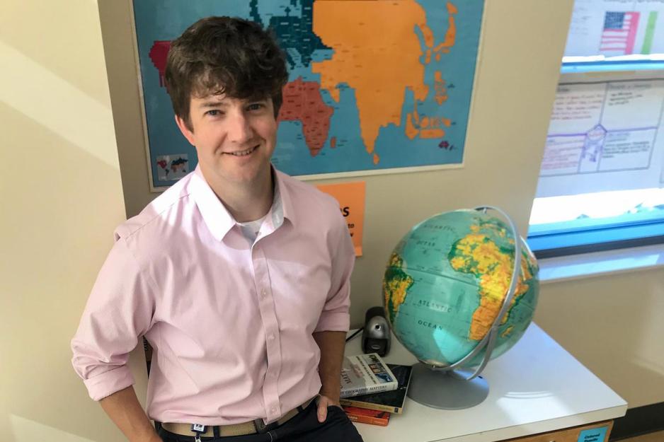 Chad Prather sits on a table next to a globe