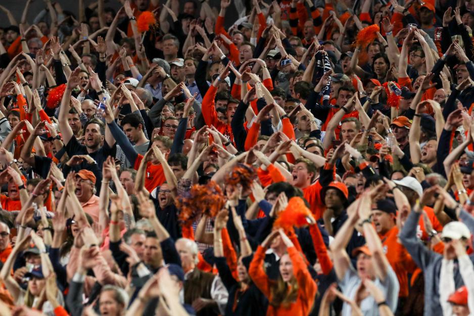 Fans make an A with their arms while cheering on the basketball team