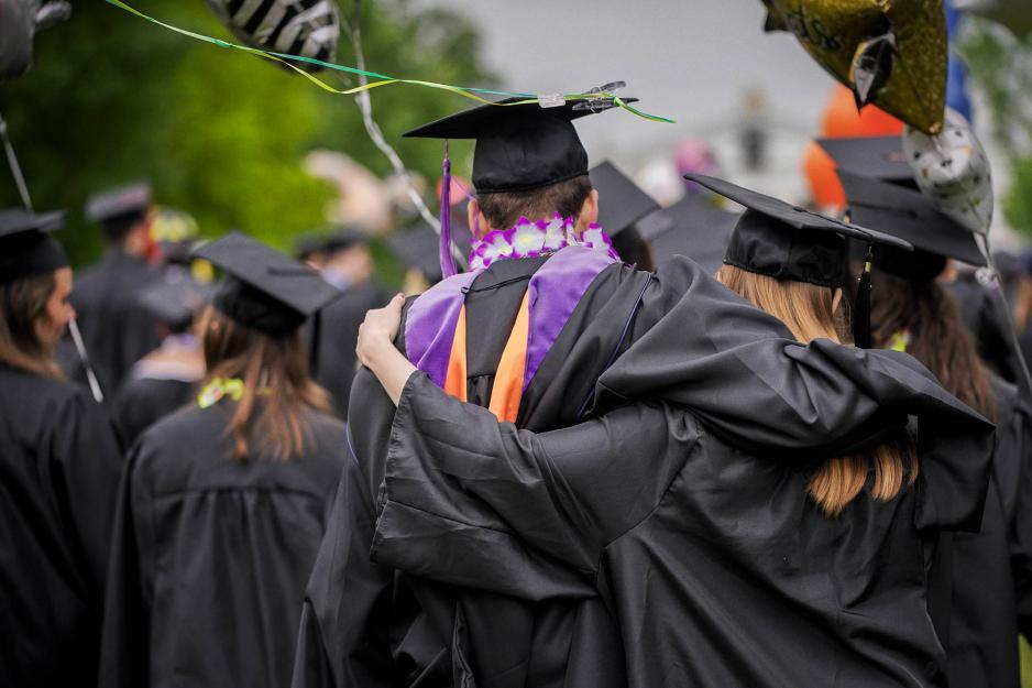 Graduates embracing each other as they walk