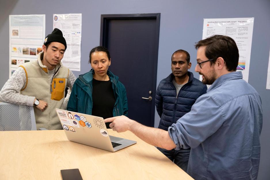 Jonathan Kropko, right, pointing to a laptop screen while three students look at the screen