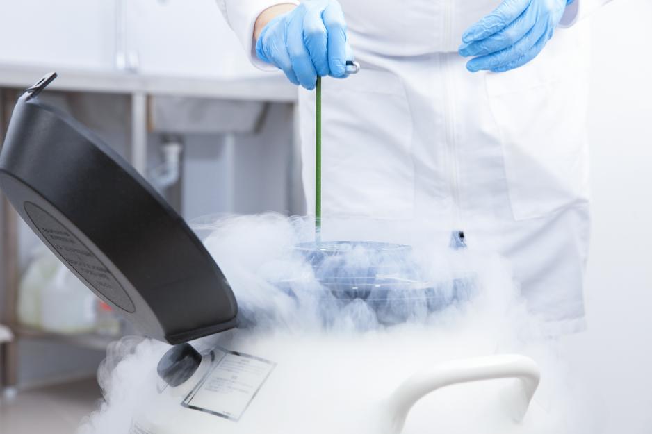 Medical Professional pulling something from a cryogenic tank while smoke comes flowing out