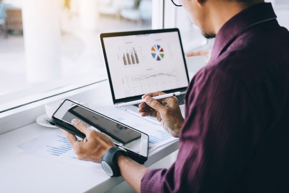 Man working on a computer and tablet looking at graphs