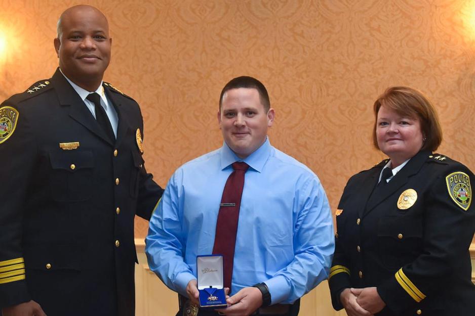 Officer Dean Dotts, center, holds a Medal her won for saving someones life while Chief Tommye Sutton, left, and Deputy Chief Melissa Fielding stand next to him