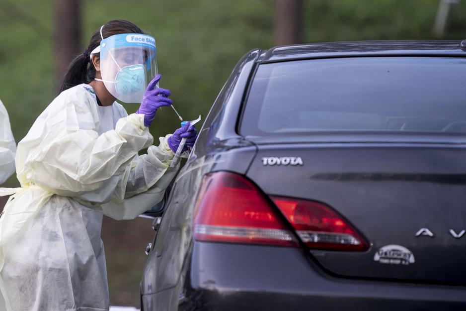 Healthcare professional giving a Covid-19 test to a vehicle passenger