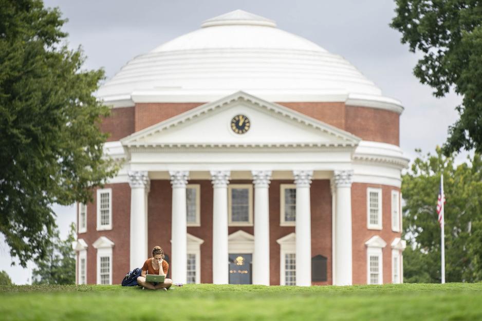 Student with laptop sitting in the grass in front of the Rotunda