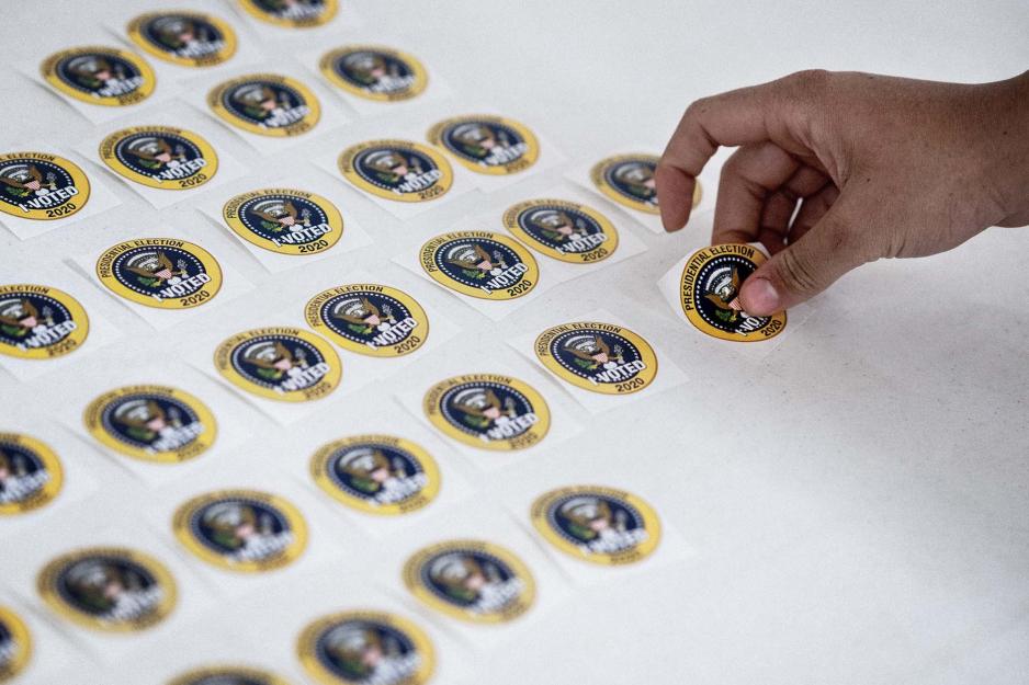 person grabbing a I voted sticker from a table