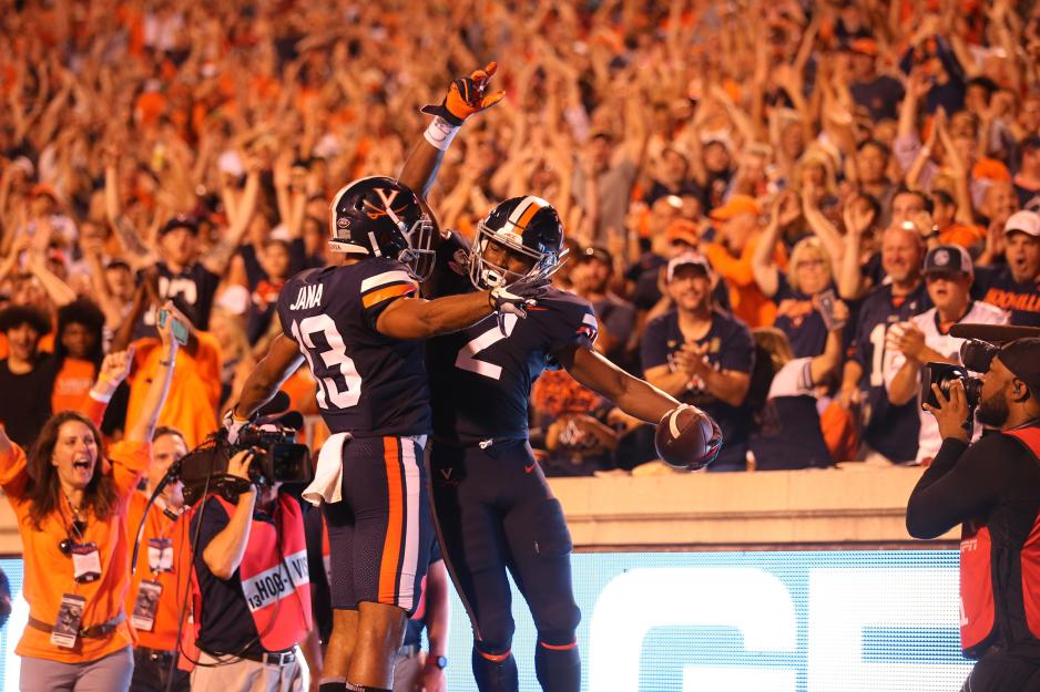 Two football players jumping up and hitting chests during a game