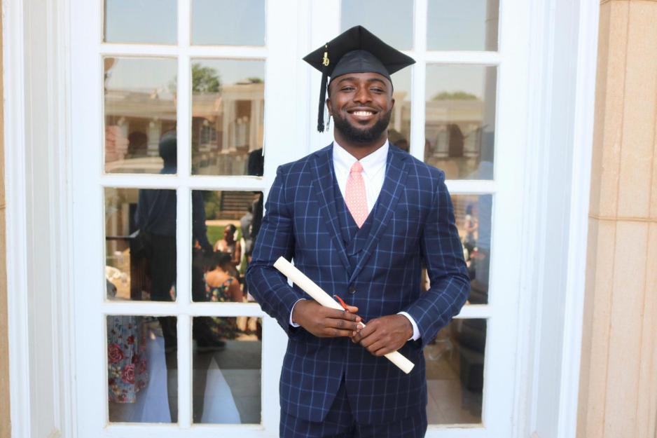 Gladimir Paul holding a diploma wearing a graduation cap