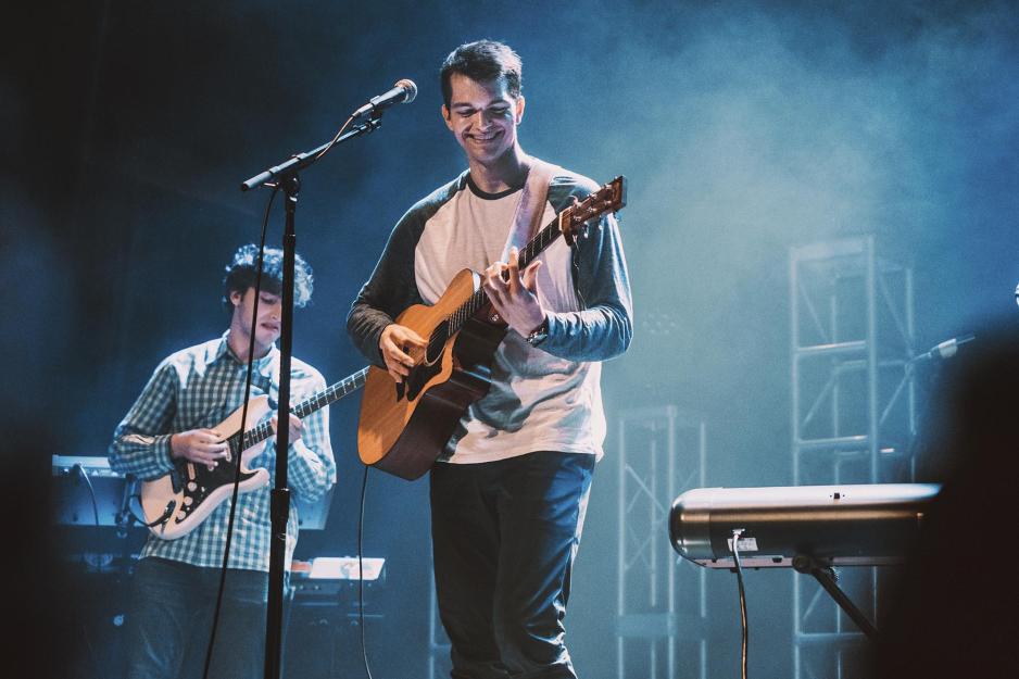 Grant Frazier on stage playing his guitar at a microphone