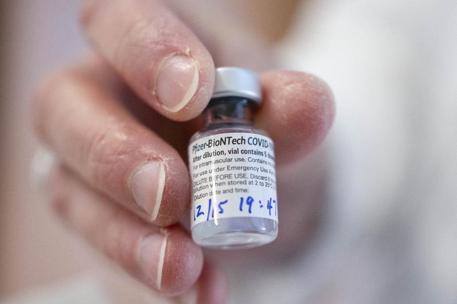 hand holding a Pfizer vaccine vial