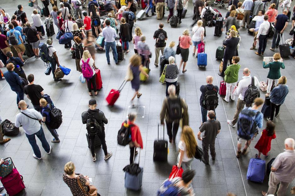 Busy airport terminal with people standing and others pulling their luggage