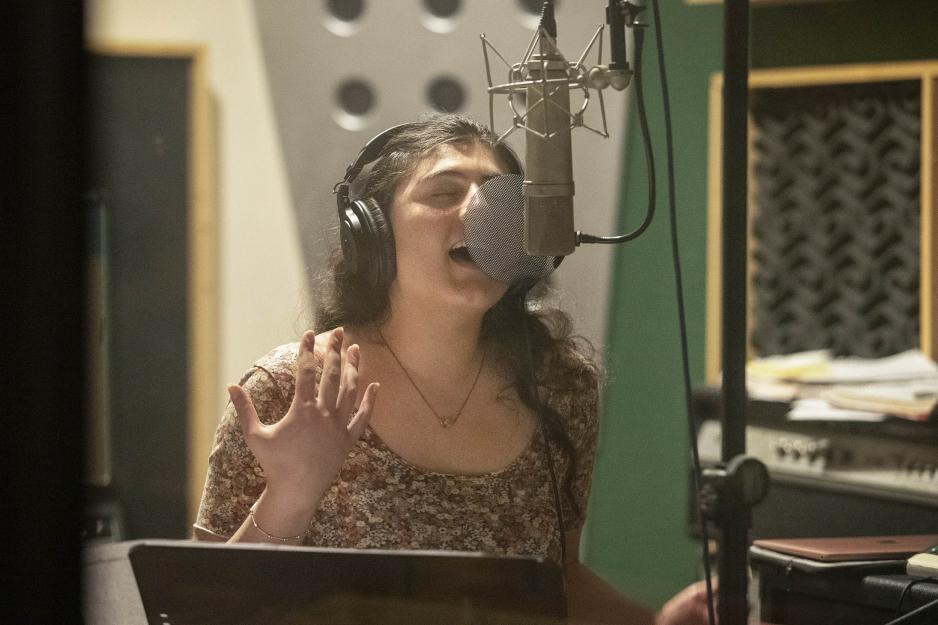 Tina Hashemi singing into a microphone at a studio