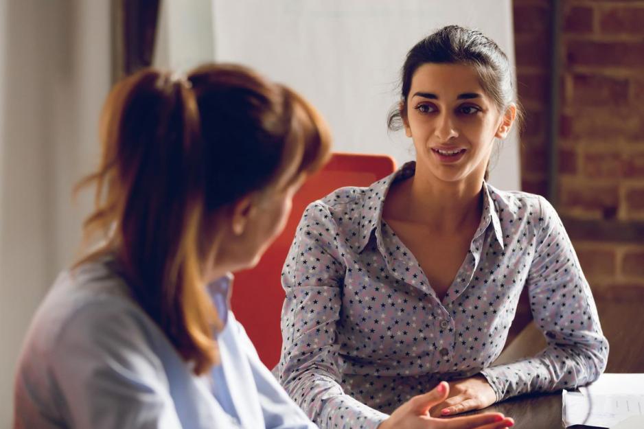 two people sitting at a table talking to each other
