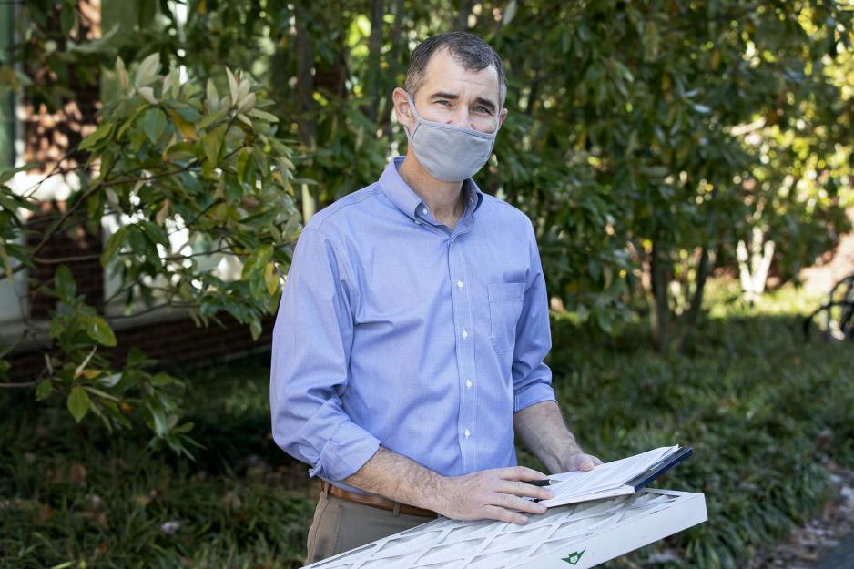 Roland Zumbrunn stands while holding an air filter and notepad
