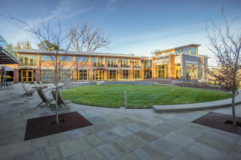 UVA building with the sun shining on half of the building with chairs on the patio