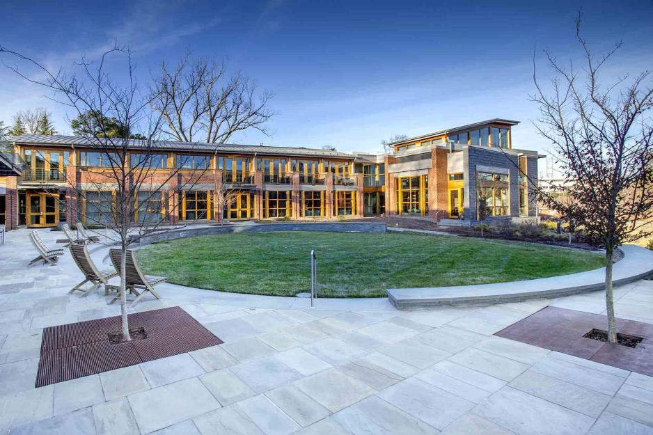 UVA building with the sun shining on half of the building with chairs on the patio