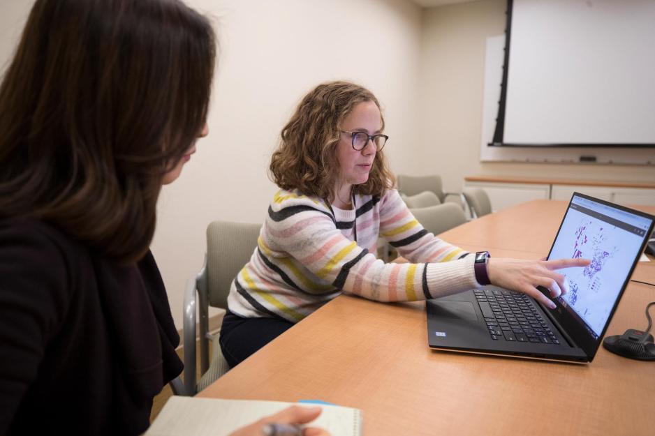 Jennifer Lobo, points to a screen while another woman watches