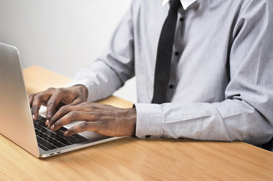 Man sitting at a desk typing on a laptop