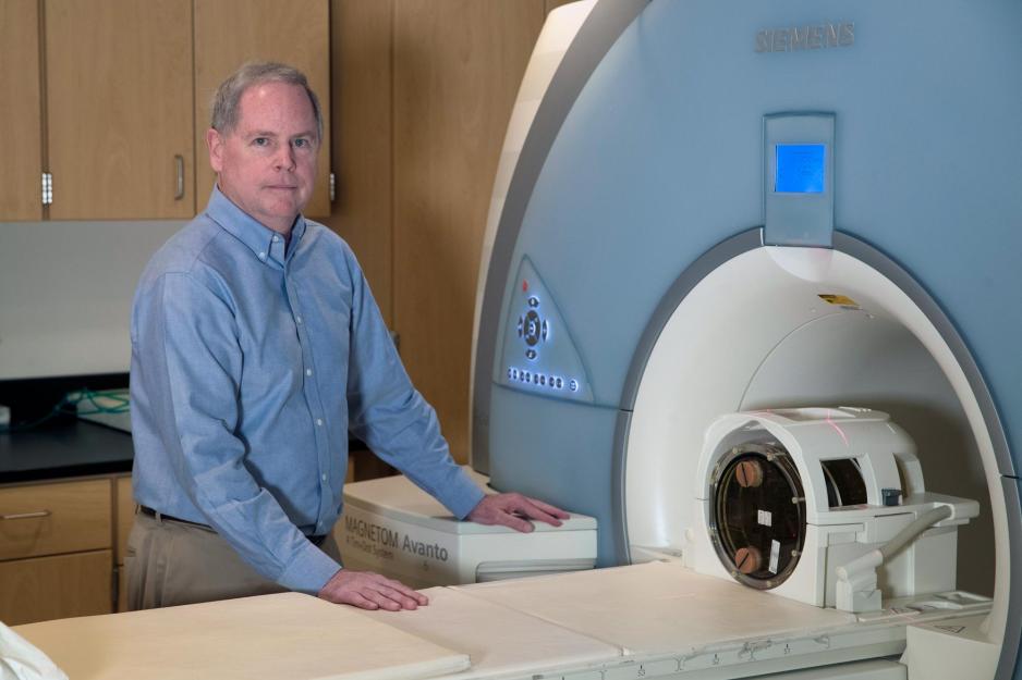 ohn Mugler stands next to a MRI machine