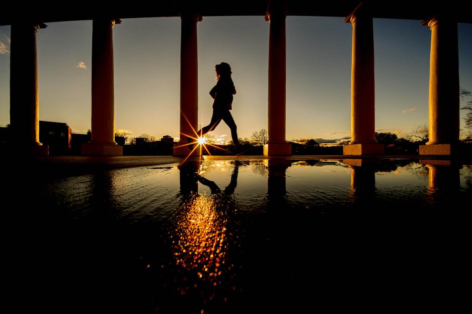 Person running at sunset through columns on grounds