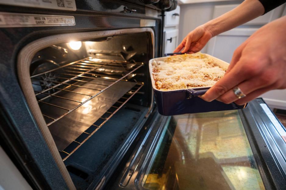 Person placing an Lasagna into an oven
