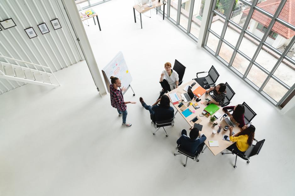 Aerial view of people at table working on a flip chart board and laptops together