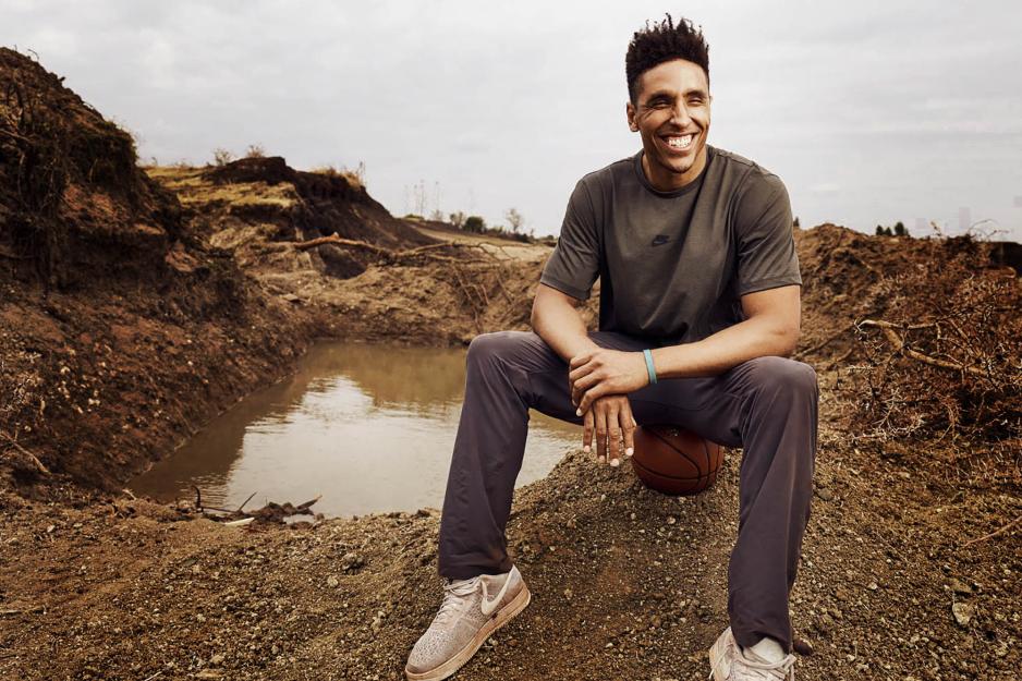 Malcolm Brogdon sits on a basketball next to a mud puddle