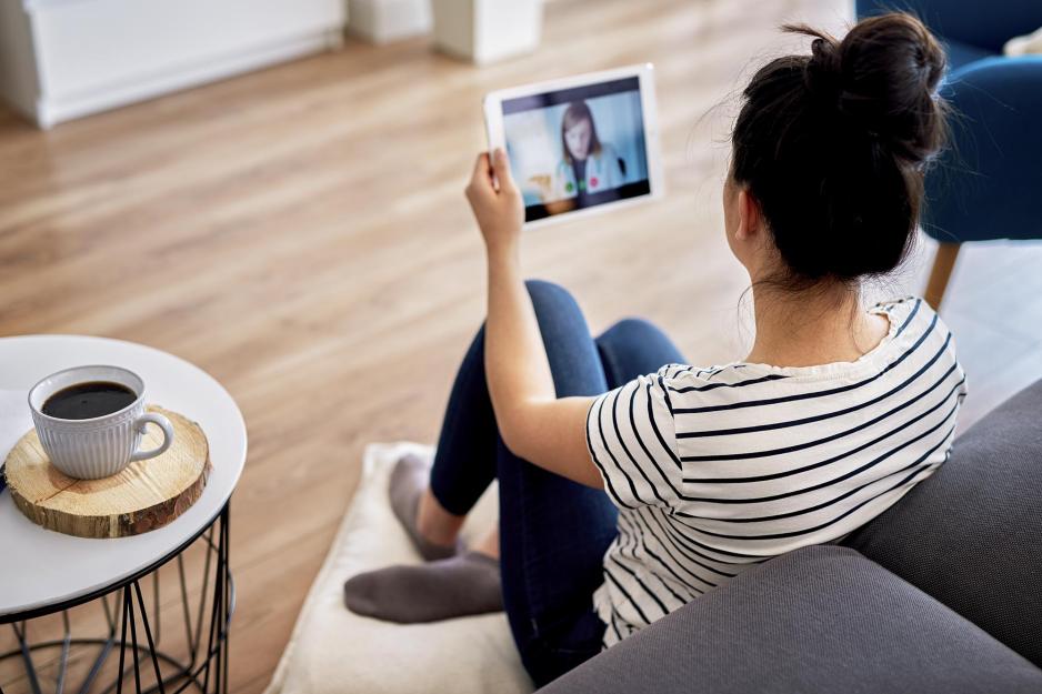 Person sitting on the floor having a video call with a healthcare professional