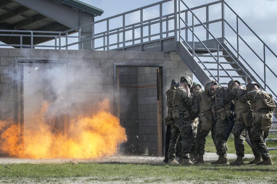 U.S. Marines team brace themselves in a line as a door is exploded on the left