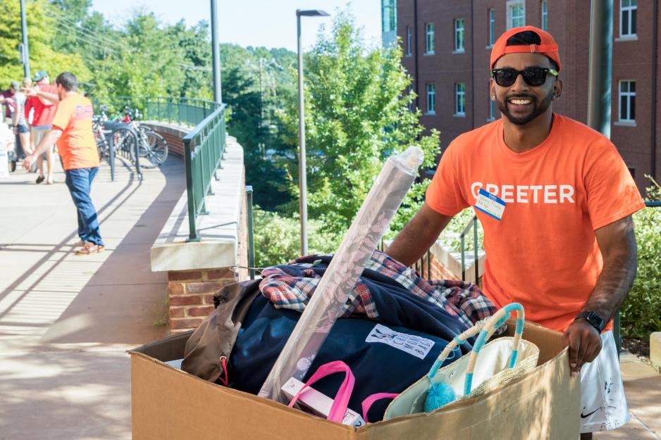 Vinny Thota helping push students belongs on a sidewalk
