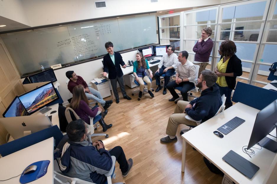 class of students sitting in a circle with one student standing and talking to their peers 