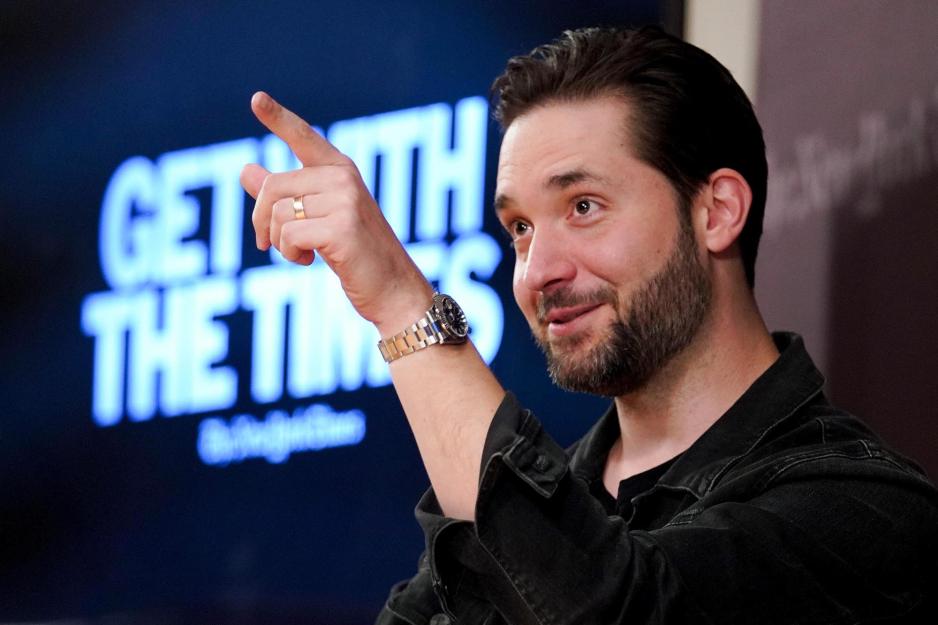 Alexis Ohanian sitting on a stage pointing to the air