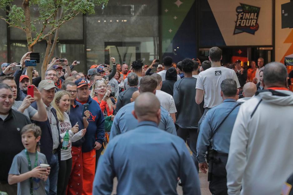 The Cavalier basketball team walking through a hotel atrium lined with fans