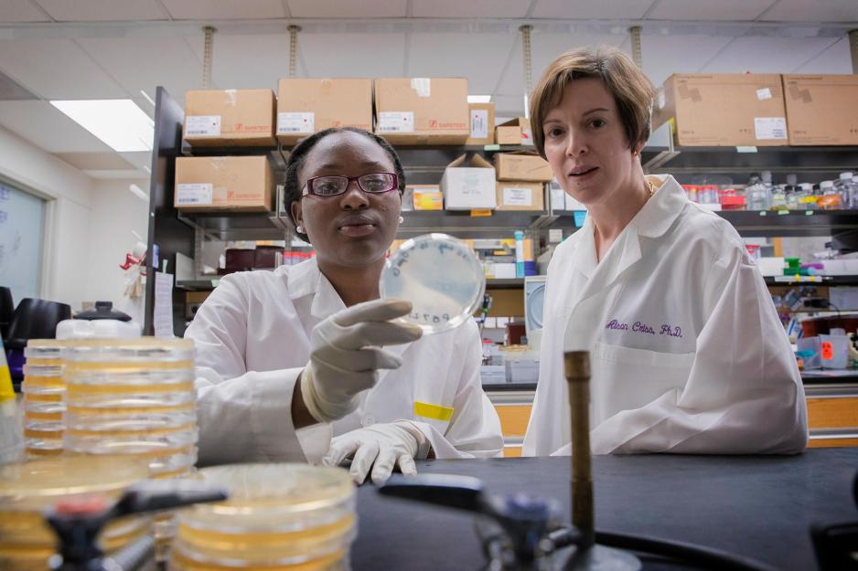 Alison Criss, right, and Princess Bush, left, hold a petri dish and look at the camera