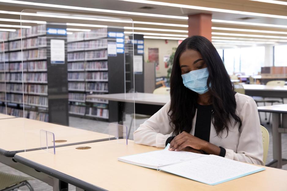 Rachel Jeffers sits at a desk between two pieces of plexiglass studying