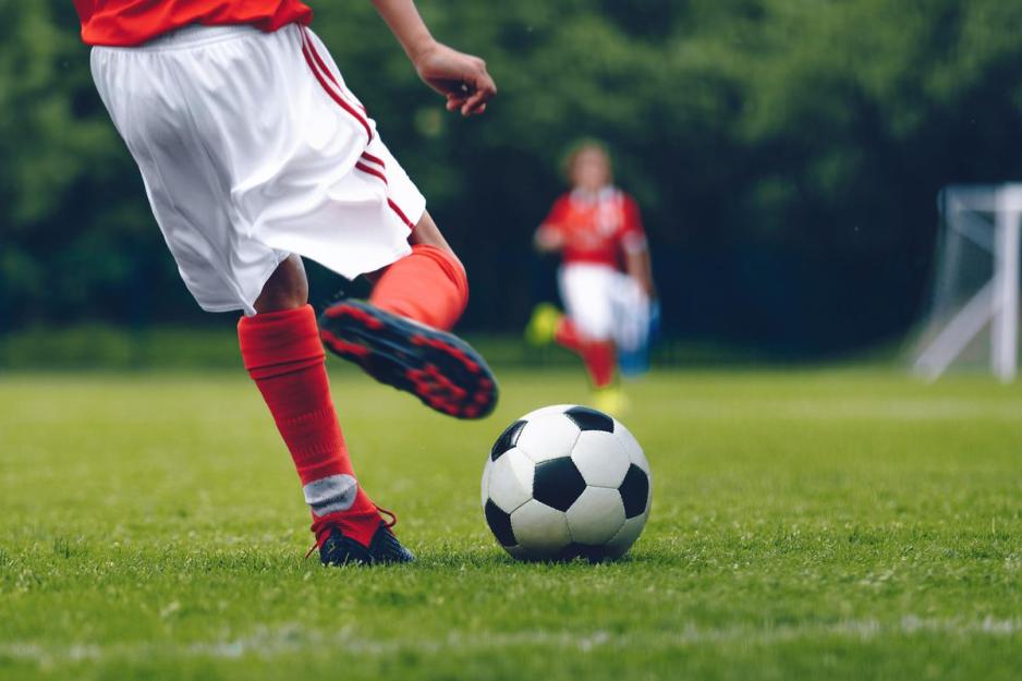 Person kicking a soccer ball during a game