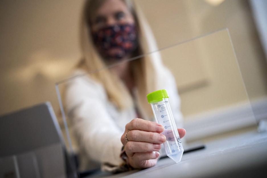 Healthcare working handing test tube to patient